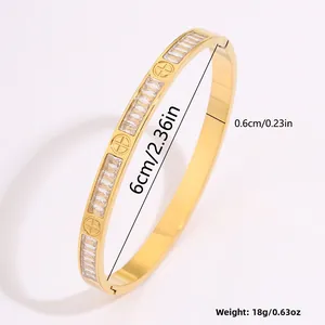 Detalle de un brazalete dorado con circonitas rectangulares y motivos florales
