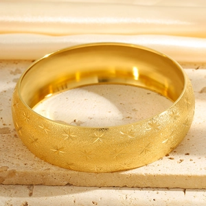 Detail of matte gold titanium steel bracelet featuring engraved star patterns and smooth inner