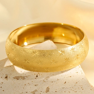 Detailed macro view of wide gold titanium steel bangle with sandblasted star pattern