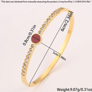 Detailed view of gold oval bangle showing size measurements and red stone inlay