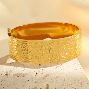 Detail shot of golden sun flower engraving on wide stainless steel cuff bracelet