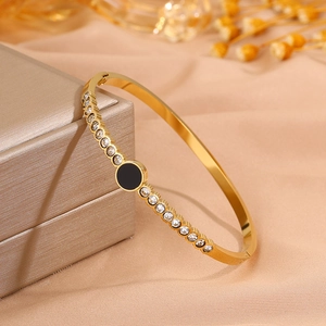Close-up of gold titanium steel bracelet with sparkling crystals and black enamel circle