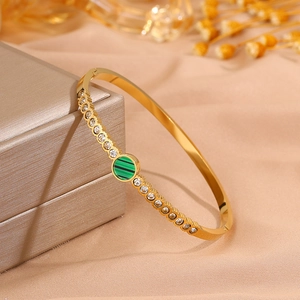 Detail of gold titanium steel bangle with inlaid white zircons and a green malachite stone