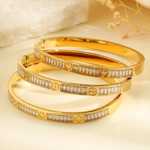 Vista detallada de pulseras doradas con circonitas y motivos de tréboles