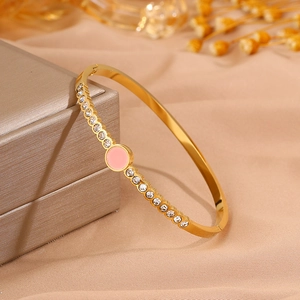 Close-up of gold titanium steel bangle with inlaid zircons and pink enamel detail