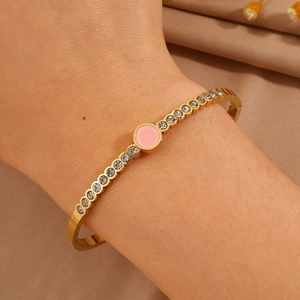 Detail of a gold titanium steel bracelet with pink center stone and crystal inlay on wrist