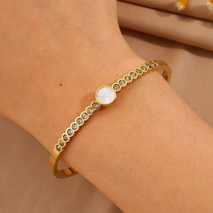 Detail of gold titanium bracelet with white shell inlay and double rows of small zircons