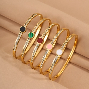 Detail of five stackable gold-plated titanium steel bracelets with colored crystal inserts