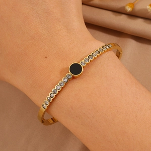 Macro shot of gold-plated bangle featuring a black round inlay and sparkling zircon accents