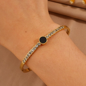 Detail of gold titanium steel bangle with black center stone and inlaid cubic zirconia