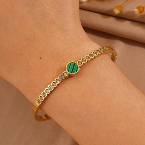 Detail of gold titanium steel bangle featuring a green malachite stone and zircon inlay