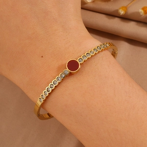Detail view of gold titanium bracelet featuring red center gem and sparkling rhinestones