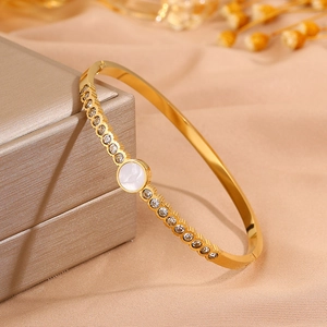 Detail of gold titanium steel bangle with mother of pearl and micro-set cubic zirconia