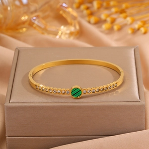 Detailed macro of gold titanium bracelet with green stone inlay and micro-pave crystals