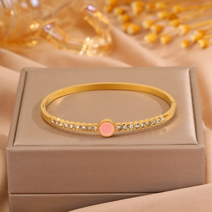 Detailed macro view of a gold-plated bangle featuring a pink inlay and side zircon accents