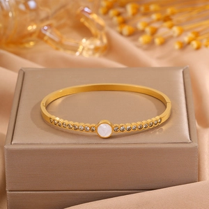 Detail of slim gold titanium steel bangle with white zircon and mother of pearl inlay