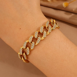 Lujosa pulsera de cadena cubana chapada en oro con pavé de cristales puesta en la muñeca