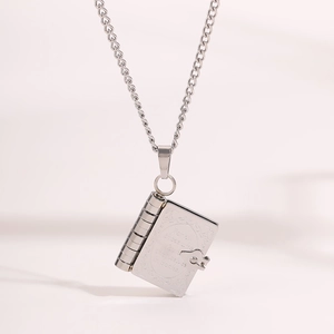 Detailed view of book-shaped pendant with engraved vintage scrollwork and quote