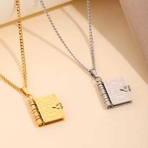 Detailed macro view of book-shaped pendants in gold and silver with engraved quotes