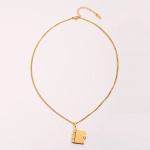 Detailed close-up of golden vintage book pendant with intricate floral engraving and chain