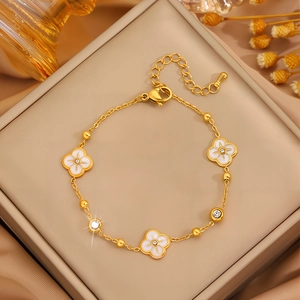 Elegantes goldfarbenes Titanstahl-Armband mit weißen Kleeblättern und Zirkonia-Sternen