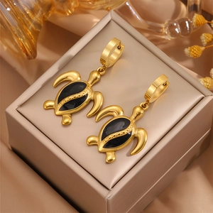 Détails des boucles d'oreilles tortue dorées avec émail noir sur soie champagne