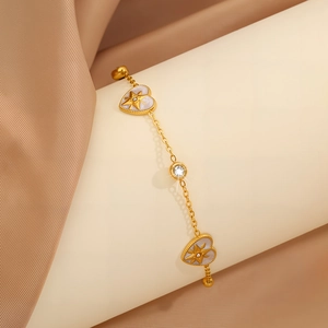 Detail von goldenen Herzanhängern mit Sternschliff und Zirkon auf einem Luxusarmband