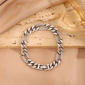 Primer plano de una pulsera de cadena Figaro plateada con cristales sobre fondo de piedra