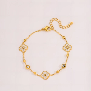 Makro-Detail des goldenen Kleeblatt-Armbands mit weißem Inlay und Zirkonia-Kristallen
