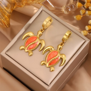 Boucles d'oreilles tortue en acier doré avec émail orange sur boîte à bijoux