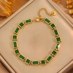 Detailed view of gold stainless steel bracelet with rectangular green gems and lobster clasp