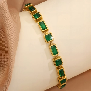 Detailed macro view of gold-plated bracelet with rectangular emerald green gemstones