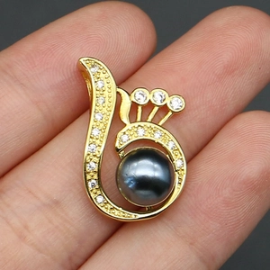Macro shot of gold-plated peacock wing pendant with grey pearl and cubic zirconia