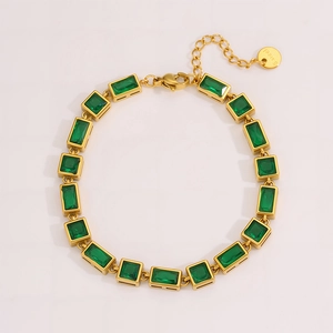 Macro detail of rectangle emerald gemstones on a gold stainless steel bracelet
