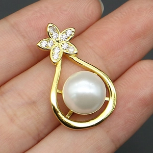 Detailed close-up of a teardrop pearl pendant with a gold-plated flower design and zircons