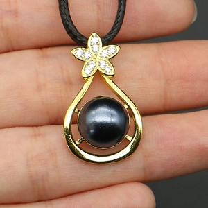 Detailed close-up of water drop pearl pendant necklace with gold floral diamond setting