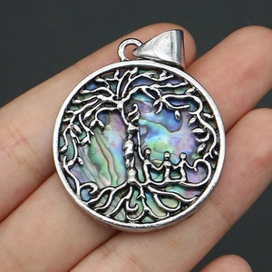 Macro shot of silver tree of life pendant featuring iridescent abalone shell inlay