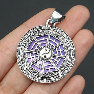 Macro detail of silver Bagua Tai Chi pendant with vibrant purple shell inlay in hand
