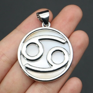 Detail of a round natural shell Cancer zodiac pendant with silver frame and hanger