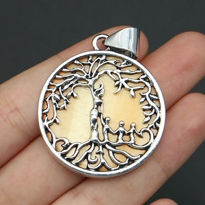 Detailed close-up of a silver tree of life pendant with family figures and shell inlay