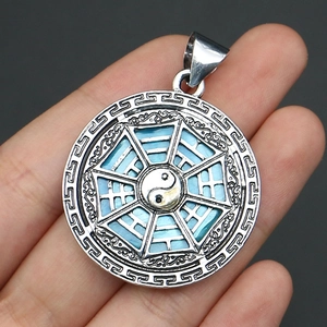Close-up of silver Tai Chi Bagua pendant with blue shell inlay and detailed carvings