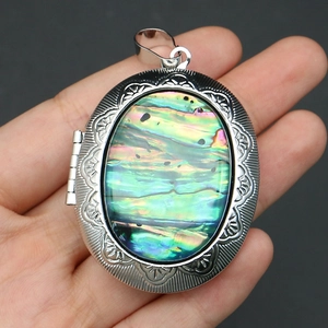 Macro detail of oval locket pendant featuring embossed floral edges and iridescent abalone shell