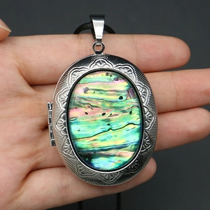 Macro detail of oval locket necklace with floral engraving and abalone shell inlay