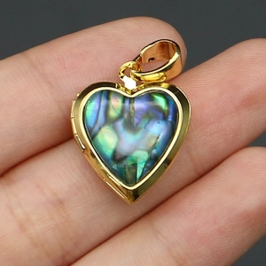 Detail view of heart-shaped locket pendant with natural abalone shell and golden frame