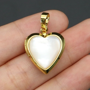 Close-up of heart-shaped locket in gold metal with iridescent mother of pearl inlay