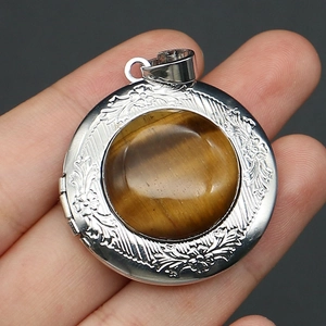 Detailed view of vintage silver locket pendant with embossed floral pattern and tiger eye stone