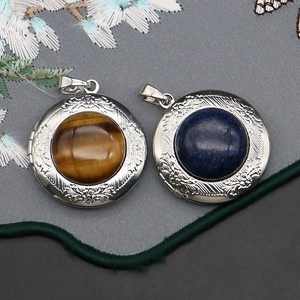 Vintage round locket pendant with tiger eye stone and floral relief on silk background