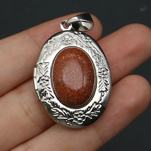 Detail of vintage silver floral locket with red-brown goldstone inlay held in hand