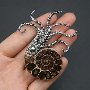 Detailed view of silver octopus fossil pendant held in hand for size and texture reference