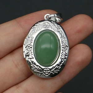Detailed close-up of a silver locket pendant with floral engraving and green stone inlay